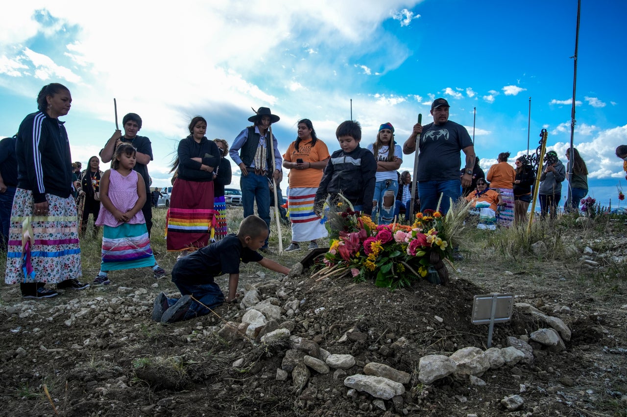 Children use rocks to mark the grave of Almeda Heavyhair after funeral services for Heavyhair and two other children who were repatriated from the cemetery at the former Carlisle Indian Industrial School to Fort Belknap Indian Reservation on Sept. 20, 2024, in Hays, Montana.