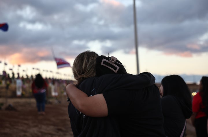 People embrace at a public hillside memorial to Lahaina wildfire victims after leis were placed over the memorial crosses before sunrise in a ceremony organized by Malu i Ka ʻUlu, on Aug. 8, 2024, in Lahaina, Hawaii.