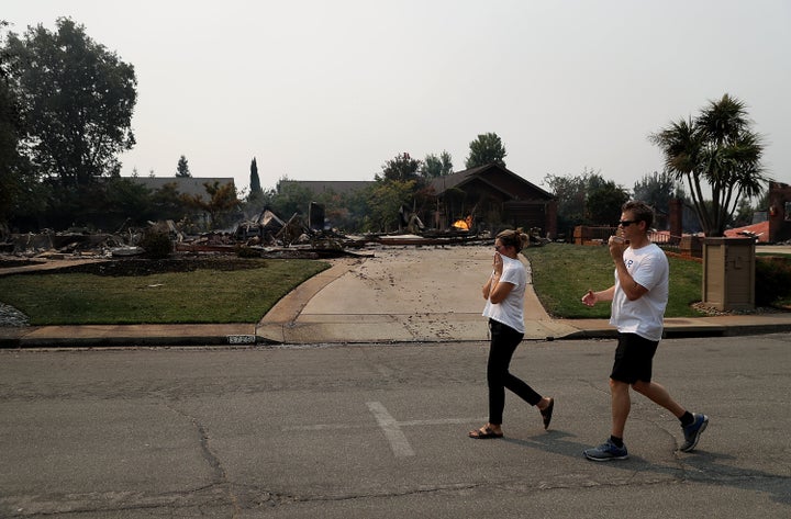 Residents walk by a home that was destroyed by the Carr fire on July 27, 2018, in Redding, California.