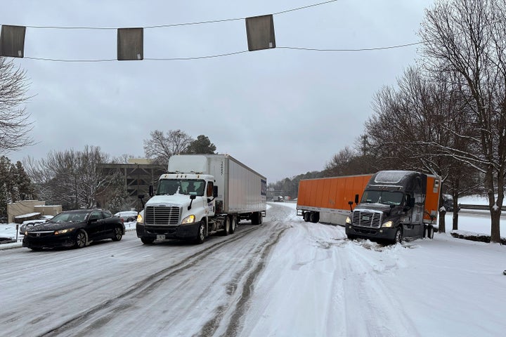 A truck is jackknifed as another spins its wheels on a slushy offramp off Interstate 285 northeast of downtown in Atlanta on Friday, Jan. 10, 2025. (AP Photo/Jeff Amy)