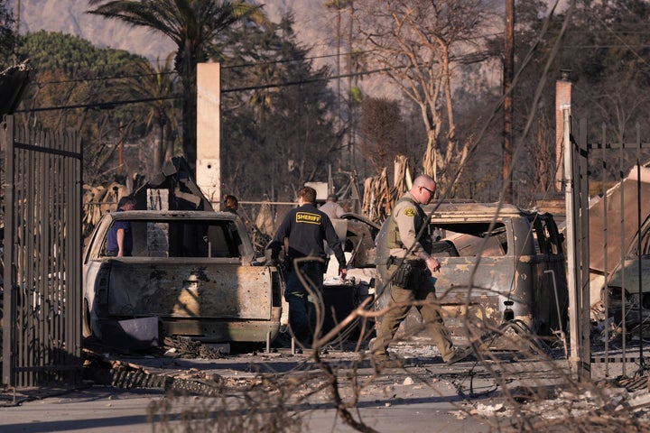 A medical examiner and sheriff's deputies check on a home destroyed by the Eaton Fire on Saturday, Jan. 11, 2025, in Altadena, Calif. (AP Photo/Mark J. Terrill)