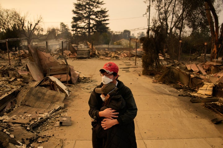 Ari Rivera, rear, Anderson Hao hold each other in front of their destroyed home in Altadena, Calif., on Thursday, Jan. 9, 2025.