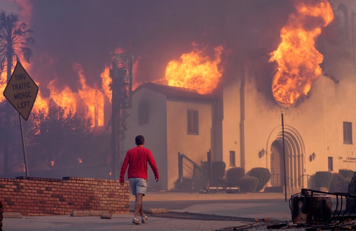 A man walks in front of the burning Altadena Community Church, on Wednesday, Jan. 8, 2025, in the downtown Altadena section of Pasadena, Calif.