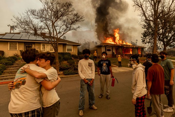 FILE - Residents embrace outside of a burning property as the Eaton Fire swept through Wednesday, Jan. 8, 2025 in Altadena, Calif. (AP Photo/Ethan Swope, File)