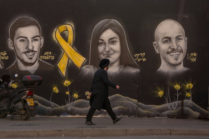 An Ultra-orthodox Jewish man walks past a graffiti wall in Jerusalem that displays portraits of hostages held by Hamas in Gaza, on Monday, Jan. 13, 2025.