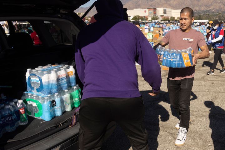 Volunteers carry water for evacuees from the Eaton Fire at a donation center in Santa Anita Park, Arcadia, California, on Jan. 13, 2025.