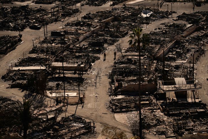 Firefighters walk along a road in a fire-ravaged community in the aftermath of the Palisades Fire in the Pacific Palisades neighborhood of Los Angeles, on Jan. 13, 2025. 