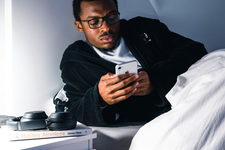 Restless man checking his phone in bed.