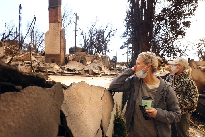 Ana Ashby, front, and her daughters Antonia and Judi, right, take in the destruction of their neighbor's home from the Pacific Palisades Fire.