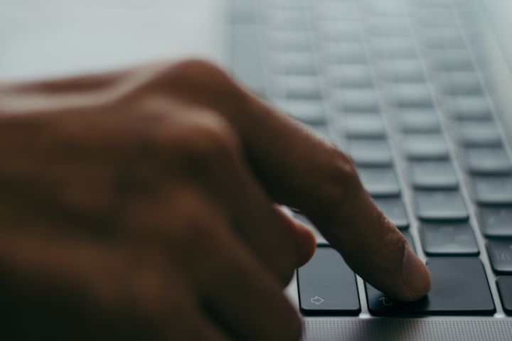 Image of an index finger pressing the Enter key on a laptop