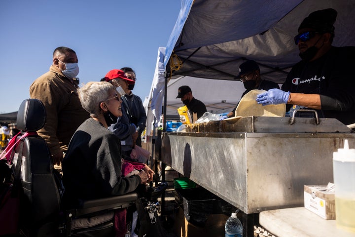 An evacuee in a wheelchair waits at a taco stand where volunteers offer food for the people displaced by the Eaton Fire in Arcadia, California, on Jan. 13, 2025.