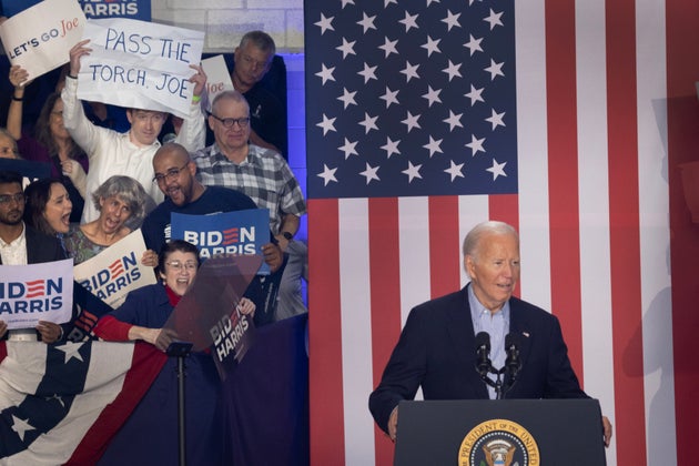 An audience member holds a sign calling on President Joe Biden to 