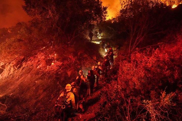 Firefighters walk up a ridge to battle the Lilac Fire in Bonsall, Calif., on Jan. 21, 2025.