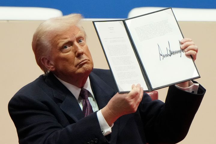 President Donald Trump holds up an executive order after signing it at an indoor presidential inauguration parade event in Washington on Monday.