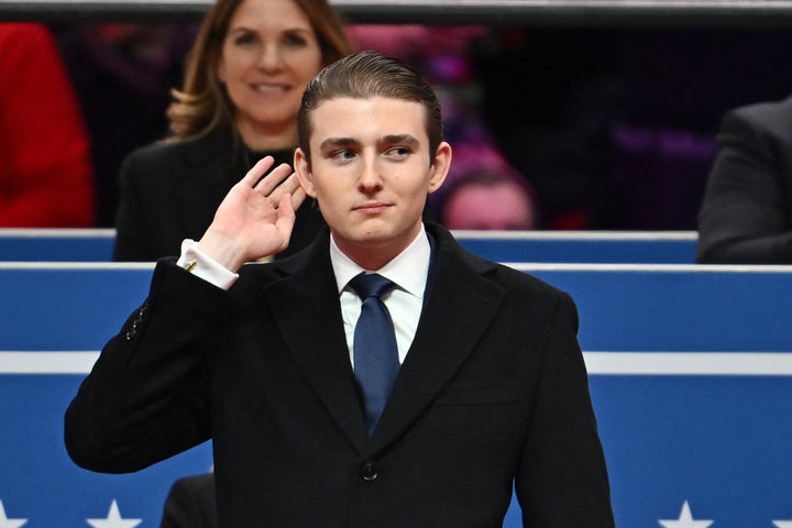 Barron Trump gestures after being acknowledged by his father at an inauguration event in Capital One Arena.