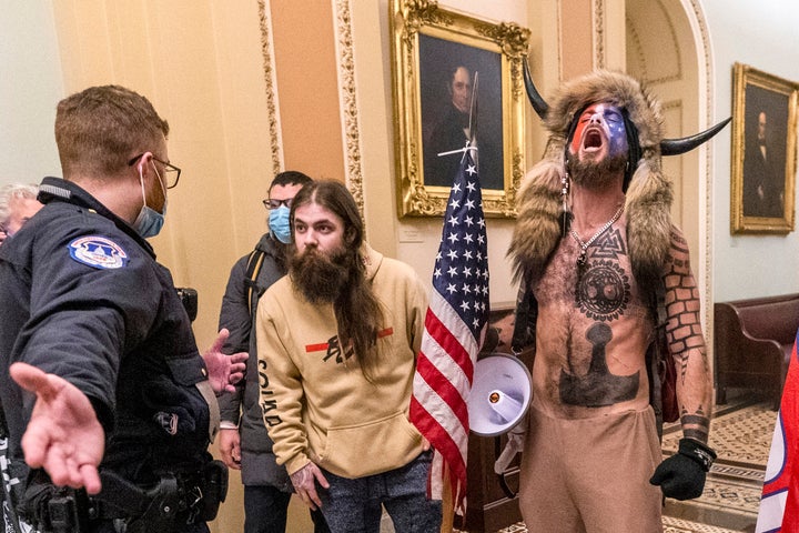 Jacob Chansley, also known as the QAnon Shaman, is confronted by U.S. Capitol Police officers outside the Senate Chamber. 