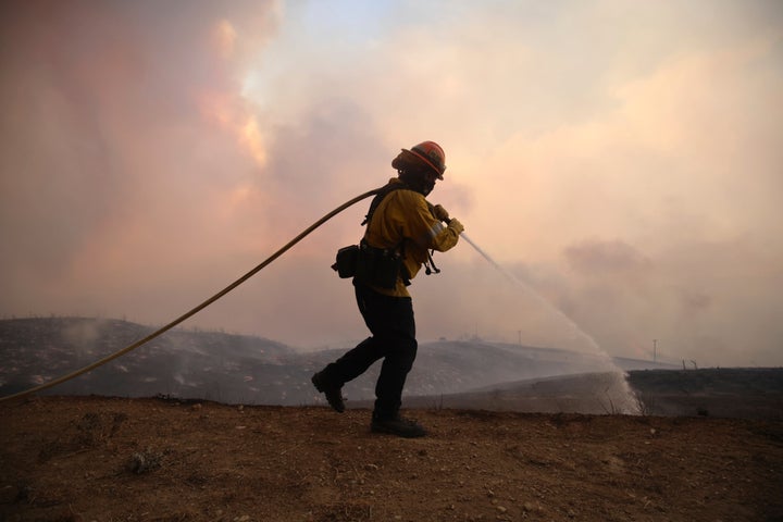 A firefighter sprays water on the ground while battling the Hughes Fire in Castaic, Calf., Wednesday, Jan. 22, 2025.