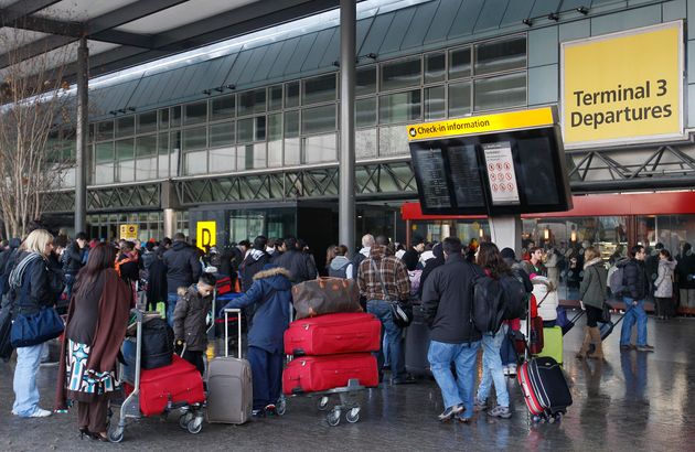 Passengers as they wait outside Terminal 3 as the doors are manned by security to prevent overcrowding inside the terminal at Heathrow Airport in London.