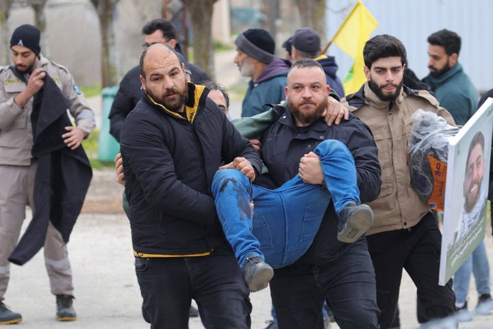 Residents carry a man injured by Israeli fire to safety in Borj El Mlouk, in the outskirts of Lebanon's Kfar Kila, on Jan. 26, 2025. Israeli forces opened fire at residents of southern Lebanon, killing at least 15 and wounding around 80, health officials said.