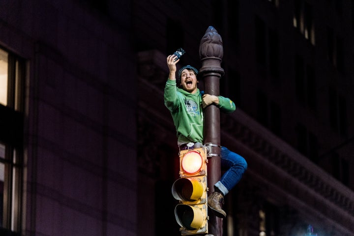 An unidentified fan climbs a pole following the Eagles playoff victory to advance to the Super Bowl. One person died after attempting the stunt.