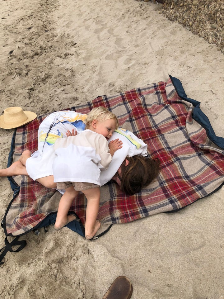 The author's toddler comforting her when she was sick on the beach during her first trimester.