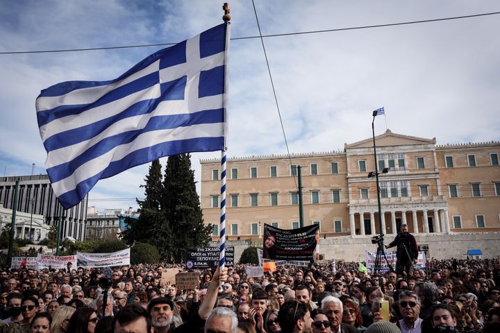 Πλήθος κόσμου κρατά πανό με συνθήματα και ελληνικές σημαίες κατά τη διάρκεια της συγκέντρωσης που διοργάνωσε ο Σύλλογος Συγγενών Θυμάτων των Τεμπών στην Αθήνα, Ελλάδα, στις 26 Ιανουαρίου 2025. (Φωτογραφία: Giorgos Arapekos/NurPhoto μέσω Getty Images)