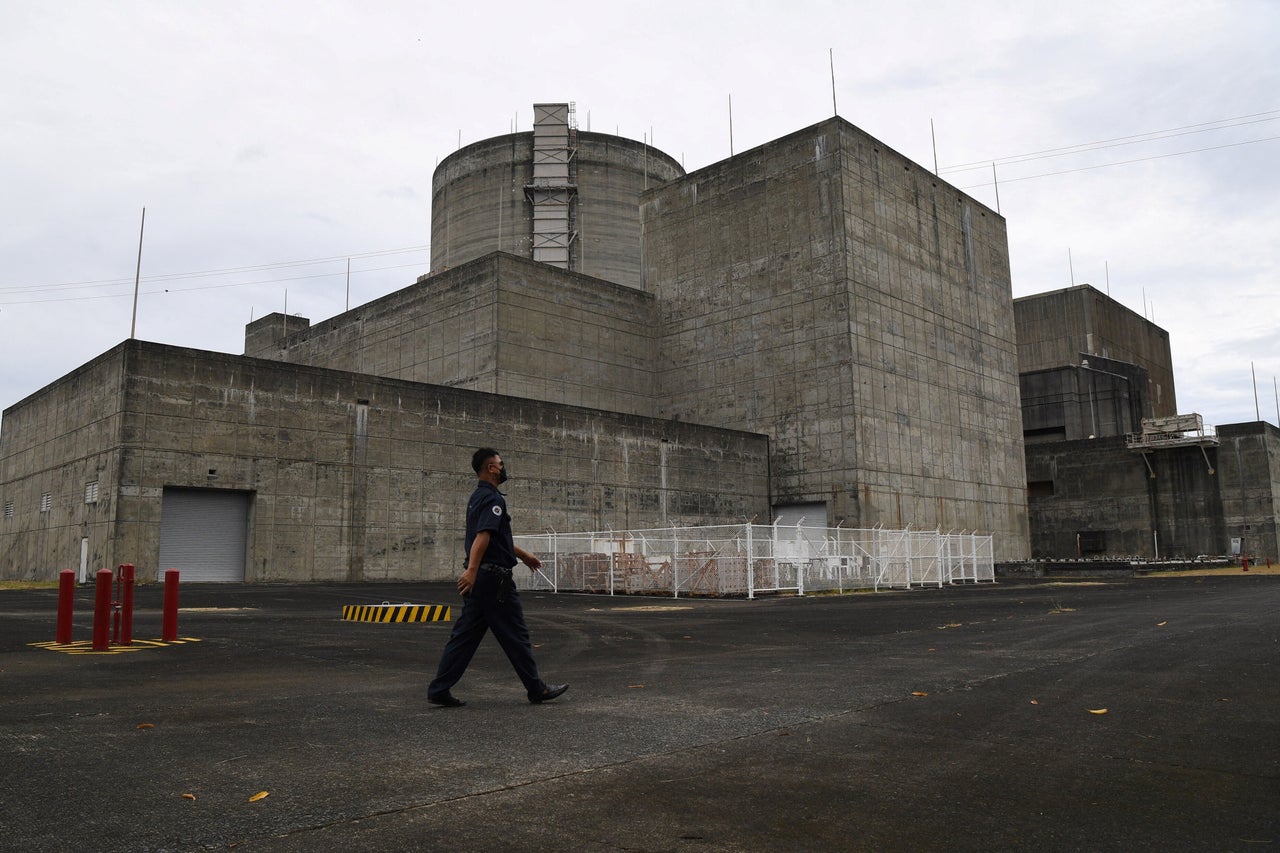 This photo taken on April 5, 2022 shows a security guard walking in front of the main gate of the Bataan Nuclear Power Plant in the town of Morong in Bataan province, north of Manila. - The nuclear power plant built in the disaster-prone Philippines during Ferdinand Marcos's regime, but never switched on due to safety fears and corruption, could be revived if his son wins the May 9 presidential poll.