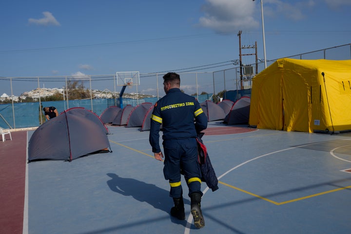 Ένας πυροσβέστης περπατάει δίπλα σε σκηνές που έχουν στηθεί σε ένα γήπεδο μπάσκετ για να φιλοξενήσουν διασώστες της Πυροσβεστικής Υπηρεσίας, καθώς οι ελληνικές αρχές λαμβάνουν μέτρα έκτακτης ανάγκης - Σαντορίνη, Δευτέρα 3 Φεβρουαρίου 2025. (AP Photo/Petros Giannakouris)