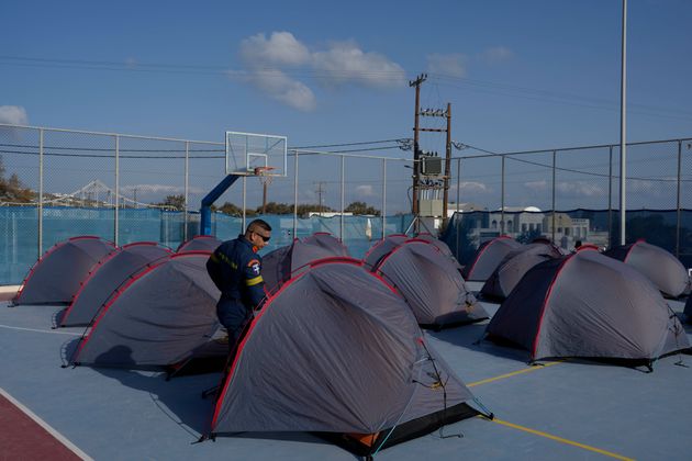 Ένας πυροσβέστης περπατάει δίπλα σε σκηνές που έχουν στηθεί σε ένα γήπεδο μπάσκετ για να φιλοξενήσουν διασώστες της Πυροσβεστικής Υπηρεσίας, καθώς οι ελληνικές αρχές λαμβάνουν μέτρα έκτακτης ανάγκης σε απάντηση στην έντονη σεισμική δραστηριότητα στη Σαντορίνη, Δευτέρα 3 Φεβρουαρίου 2025. (AP Photo/Petros Giannakouris)