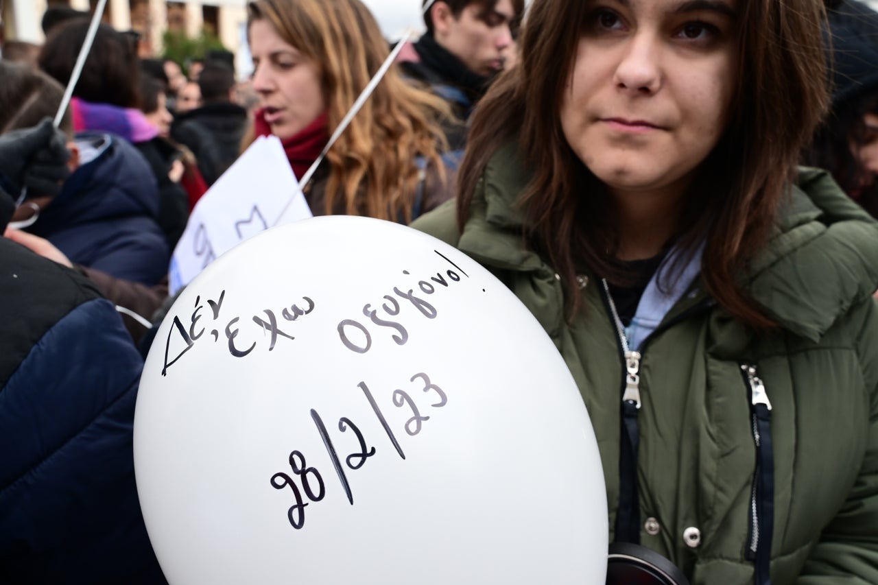 Μια γυναίκα κρατάει ένα λευκό μπαλόνι, στο οποίο αναγράφεται η φράση «Δεν έχω οξυγόνο», που συνδέεται με την τραγωδία των Τεμπών