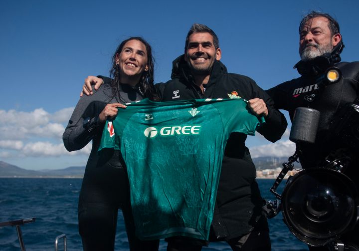 Real Betis foundation director Rafael Muela (center), with divers, holds up a new kit for Spanish Liga team Real Betis Balompie which is made from algae and plastics collected from the bottom of the sea.