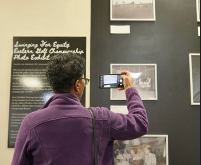 A visitor takes a photo of the "Swinging For Equity" exhibit.