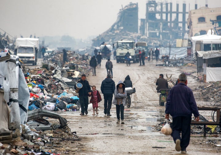 A man carries a tabla drum as he walks with a child past rubble in Jabalia in the northern Gaza Strip on February 10, 2025 amid the current ceasefire deal in the war between Israel and Hamas. (Photo by BASHAR TALEB / AFP) (Photo by BASHAR TALEB/AFP via Getty Images) 