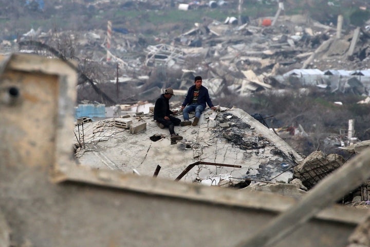 Palestinian youths sit on the rubble of a building in al-Mughraqa in the central Gaza Strip on Feb. 10, as displaced people return home amid the current ceasefire deal in the war between Israel and Hamas.