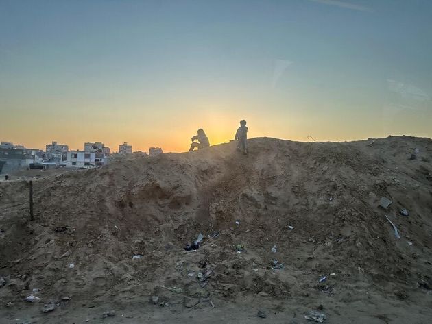 Two Palestinian youth sit on a mound in southern Gaza, following the Israel-Hamas ceasefire agreement.