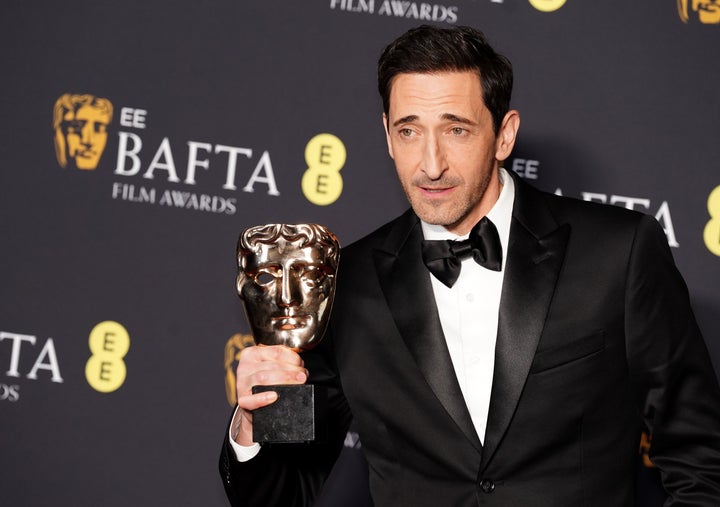 Adrien Brody holds up trophy after earning the Best Actor in a Leading Role award for "The Brutalist" at Sunday's BAFTAs in London.
