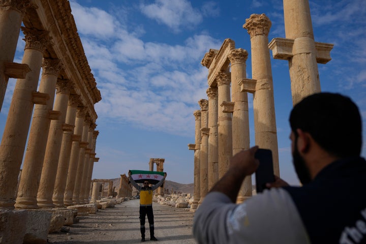 Ένα μέλος της Συριακής Πολιτικής Άμυνας (Λευκά Κράνη) φωτογραφίζει τον συνάδελφό του που κρατά τη νέα συριακή σημαία στην αρχαία πόλη της Παλμύρας, Συρία, Ιανουάριος 2025. (AP Photo/Khalil Hamra)