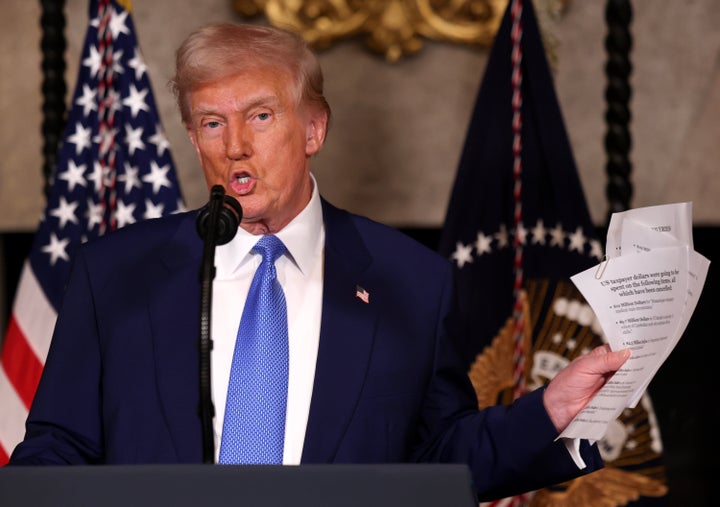 US President Donald Trump holds up paperwork during a press conference that he said listed some of the items DOGE has found to be improper government spending at his Mar-a-Lago resort on February 18, 2025