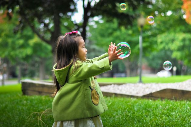 A little girl chasing after a bubble