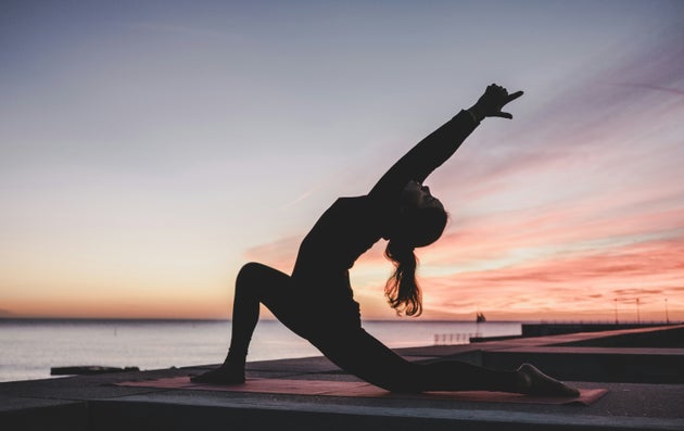 Silhouette of a woman doing yoga in front of a sunrise