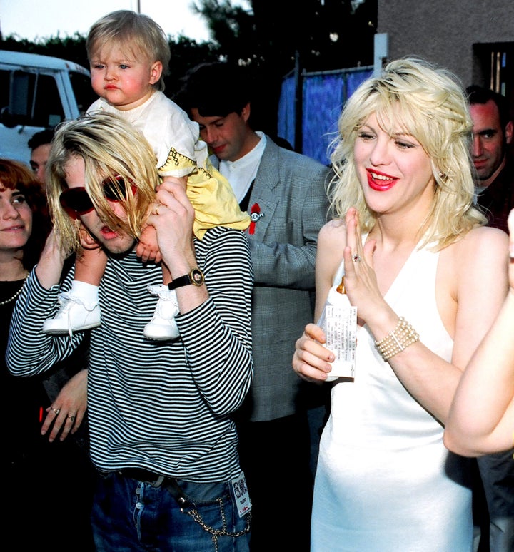 Frances Bean Cobain sits atop of her dad’s shoulders alongside her mother, Courtney Love, in 1993.