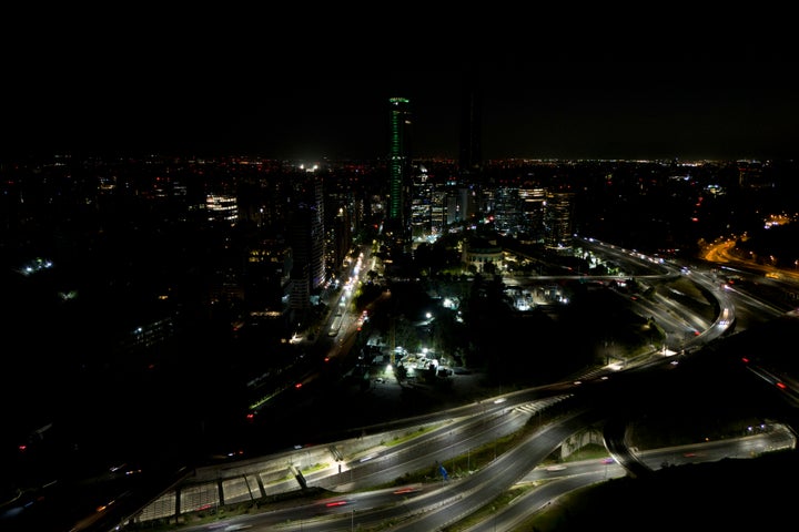 Cars zip past dark buildings during a power outage in Santiago, Chile, on Feb. 25, 2025.