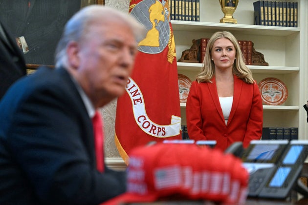 White House Press Secretary Karoline Leavitt (R) looks on as US President Donald Trump speaks to the press next to hats reading 