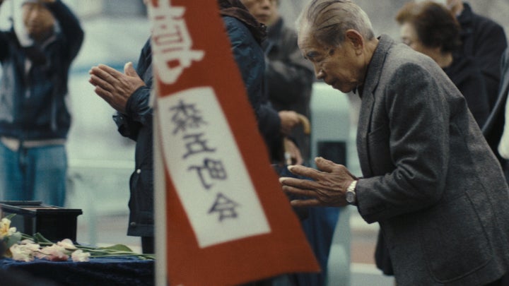 映画より。森下五丁目の八百霊地蔵尊で開かれた慰霊祭で、手を合わせる築山実さん