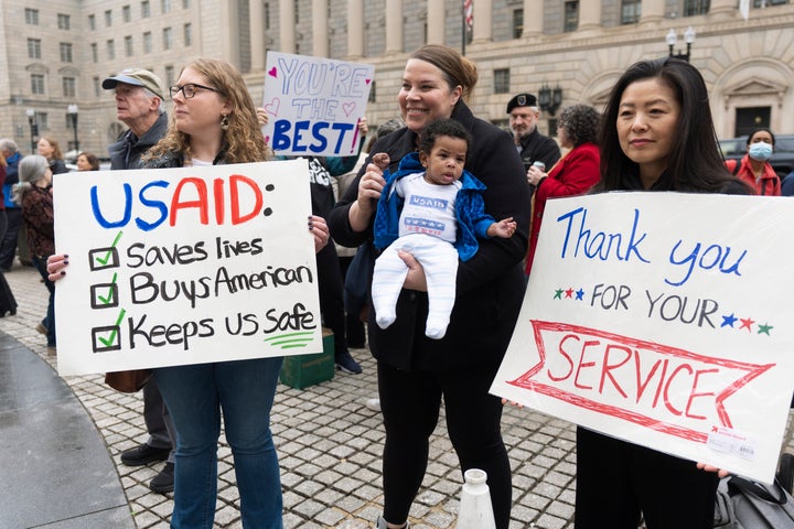 Supporters hold banners as USAID workers retrieve their personal belongings from the agency's headquarters in Washington on Feb. 27, 2025. 