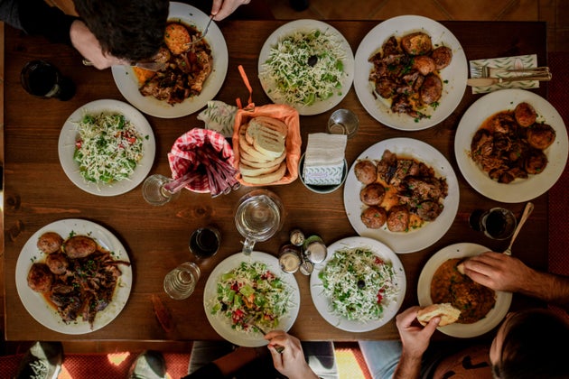 A bustling dinner party over a table laden with delicious courses