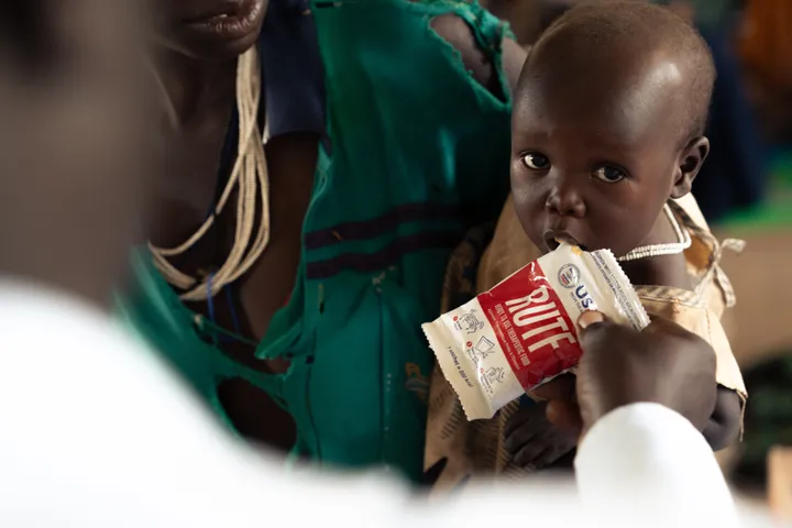 A child eats from a packet of a nutrient-dense peanut butter called RUTF, or ready-to-use therapeutic food, that's manufactured in Georgia.