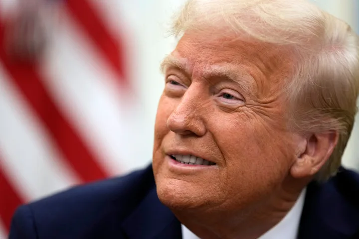 President Donald Trump smiles as he signs executive orders in the Oval Office of the White House, Jan. 23, 2025, in Washington. 