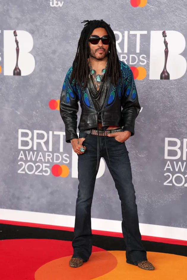 Lenny Kravitz in a peacock leather jacket and jeans with leopard print shoes