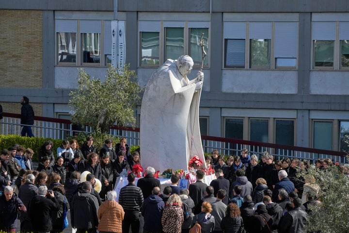 Faithful gather in prayer around the statue of John Paul II outside the Agostino Gemelli Polyclinic where Pope Francis is hospitalized, in Rome, Sunday, March 2, 2025. (AP Photo/Gregorio Borgia)